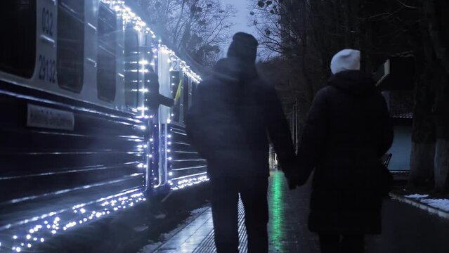 Couple Holding Hands, Walking and Waving to Departing Train in Winter Park
