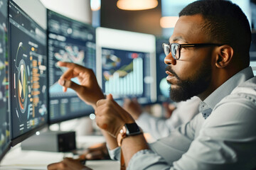 A professional man analyzes data on a computer screen with graphs and charts in a modern office setting.