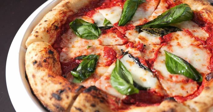 Margherita pizza with mozzarella cheese, tomato sauce, olive oil and basil leaves.
