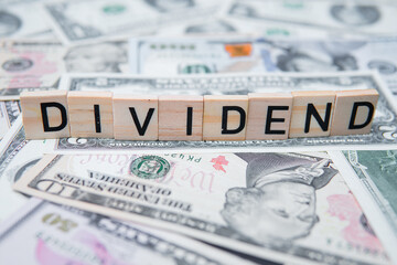 The inscription dividend on the background of American dollars. Investing in Dividend Aristocrats