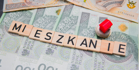 The inscription Mieszkanie next to Polish money and a red house. A concept showing the purchase of an apartment. Mortgage loan and real estate market in Poland