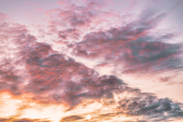 A beautiful sky tinted by the sun leaving vibrant shades of gold, pink, blue and multicolored. Clouds in the twilight evening and morning sky. Cloudy sky background in the evening and during the day.
