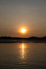 Sunrise view with colorful sky and the sea, with silhouette of the forest on the background