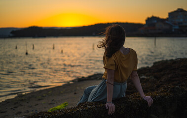 Fototapeta premium Seascape during golden sunrise with beautiful sky. Woman on the beach. Young happy woman in a yellow fluttering dress walks along seashore. The girl looks at the magical sunrise. Above view. Top view