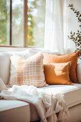 A sofa with white and orange pillows and a white blanket
