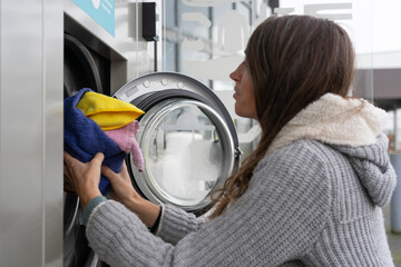 Woman putting a washing machine in a laundromat