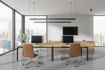 Office interior with desk and pc monitors in row, tv screen and panoramic window