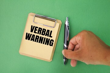 hand holding pen and paper board with verbal Warning word