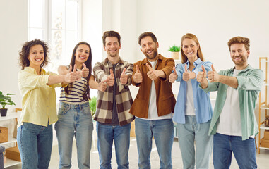 Fototapeta premium Portrait of a group of people friends men and women in casual clothes looking at the camera, showing thumbs up sign and smiling. Happy students or coworkers standing together in a row.