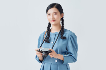 A happy and smiling young woman using a digital camera isolated on a white background.