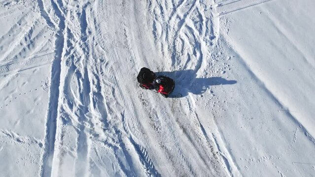 Top view of ATV riding in snowy field. Aerial shot