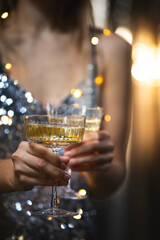 The girls pour champagne into round glasses. Women in a sparkling dress. Full cocktail creamers - le coupe