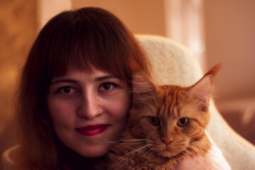 Portrait of a beautiful young woman with orange Maine Coon cat.