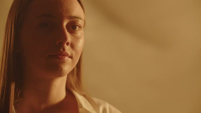 Young beautiful woman posing serious expression on blinking light background. Charming girlfriend waiting for partner. Nice confident girl looking curious her flashbacks