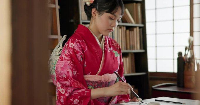 Japanese woman, writing and calligraphy for traditional poetry, creativity or art with drawing in home. Girl, person or writer with ink, pen or thinking with ideas, vision or paper for haiku in Tokyo