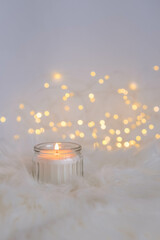 Burning candles on a white fur background with bokeh lights