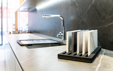 Photo of the interior of a studio kitchen. In the foreground is a display of samples of kitchen...