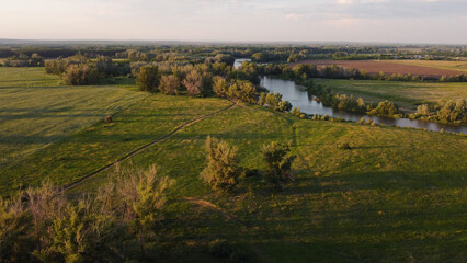a river, a green field with trees and a country road