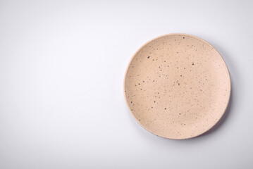 Empty round ceramic plate on a plain background, flatley with copy space