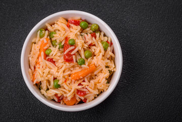 Delicious boiled rice with vegetables peppers, green peas, salt, spices and herbs