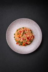 Delicious boiled rice with vegetables peppers, green peas, salt, spices and herbs