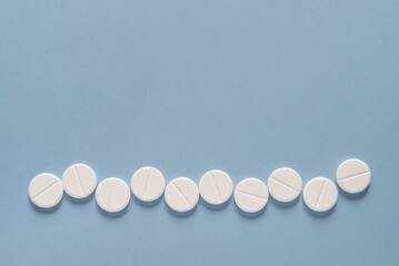 Scattered row of white round pills on blue table. Mock up for special offers as advertising, web...