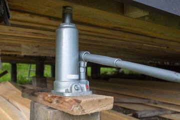 hydraulic jack for moving and raising the level of the house to a higher one. Wooden floor in the...