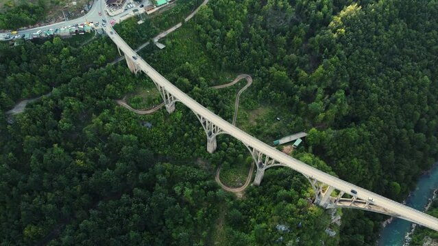 Aerial drone view of arched Djurdjevica Bridge with moving cars over Tara river canyon in Montenegro, green landscape in summer. Popular tourist destination near Zabljak town in Durmitor National Park