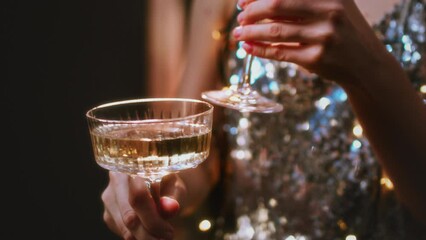 A beautiful girl holds glasses of champagne in her hands. Le coup cocktail glasses. Celebrates the New Year or a corporate holiday. Disco or retro style.