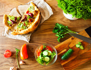 Homemade pizza and vegetables on wooden table