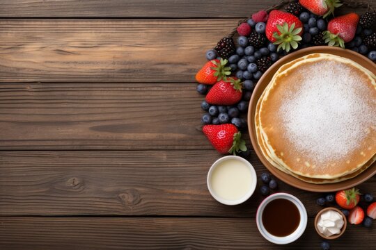 pancakes on a wooden background with berries, honey and sour cream in bowls. view from above. 