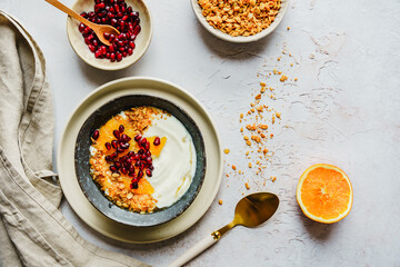 Müsli Schüssel mit Joghurt und frischen Orangen auf einem grauen Tisch. Draufsicht.
