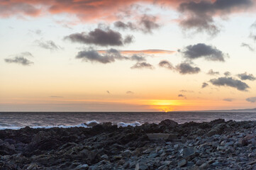 Fototapeta premium imagen del atardecer en la playa, con las rocas en la parte inferior y el cuelo con nubes 