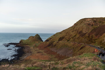 imagen de un paisaje de costa, con las colinas sin vegetaci&oacute;n verde, el cielo nublado y el mar