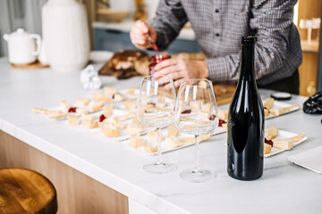 Wine Tasting Preparation with Cheese Pairings. Sommelier prepares for a wine tasting event, carefully pairing various cheeses with wines, featuring an unopened bottle and elegant glasses.