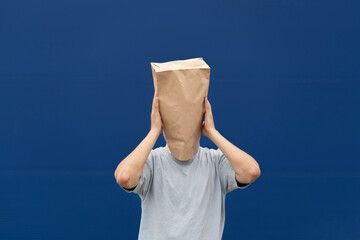person with a blank paper bag on his head show emotions, blue background