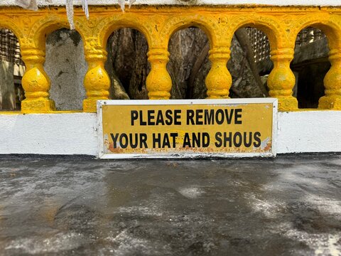 misspelled yellow sign at sightseeing spot Kothduwa Rajamaha Viharaya, Sri Lanka Please remove your hat and shous 