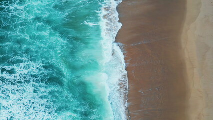 Drone shot turquoise sea waves washing empty tropical beach. Foamy ocean water.