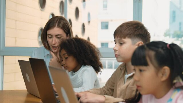 Smart teacher teaching and looking student using laptop at classroom. Professional instructor explained about programing engineering code or prompt while studying and learning program. Erudition.
