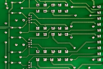 Conductor traces with silver drops of solder on a green electronic circuit. Computer board with...