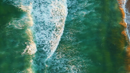 Drone shot turquoise ocean waves washing sand beach. Foamy sea swell rolling