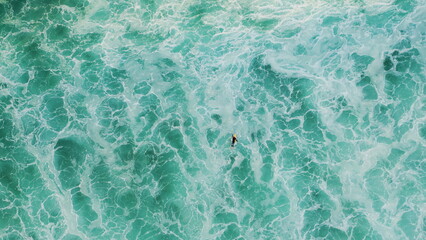 Top view surfer swimming on surfboard at sea waves. Aerial ocean water foaming.