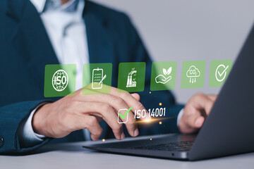 ISO 14001 concept. Businessman use laptop with ISO 14001 certified for environmental management systems (EMS). Identify, control and reduce the environmental impact of activities. - obrazy, fototapety, plakaty