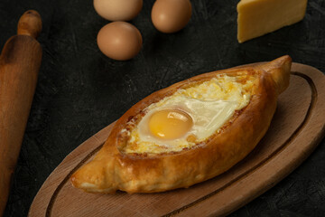 . Caucasian flatbread adjarian khachapuri with egg on a dark wooden . Adjarian Khachapuri Georgian cheese bread