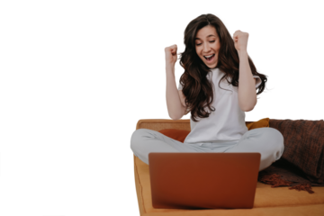 Excited brunette woman in casual sits on sofa celebrates looks at laptop clenches fists like winner with wide opened mouth against transparent background, happy businesswoman astonished