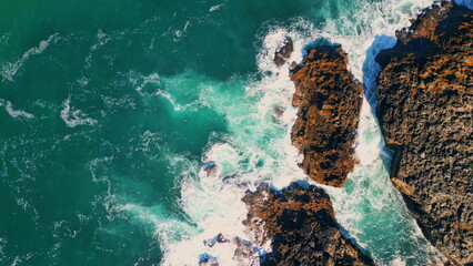 Stormy turquoise sea waves splashing at seashore cliffs. Aerial view seashore 