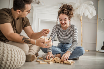 Young couple woman and man play Jenga game at home