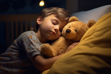 A little boy with a dreamy smile sleeps hugging a toy bear in a dark room illuminated by a cozy light.