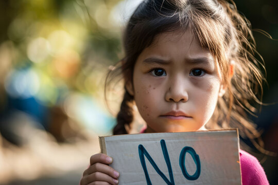 Young kid girl holding a sign with written word No to stop war or violence against children , against abuse or racism concept image