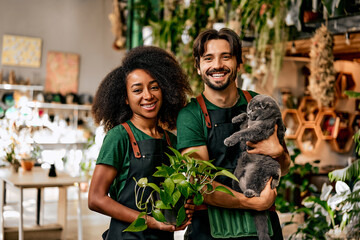A successful multinational smiling family of small business owners of a plant shop. The woman is...